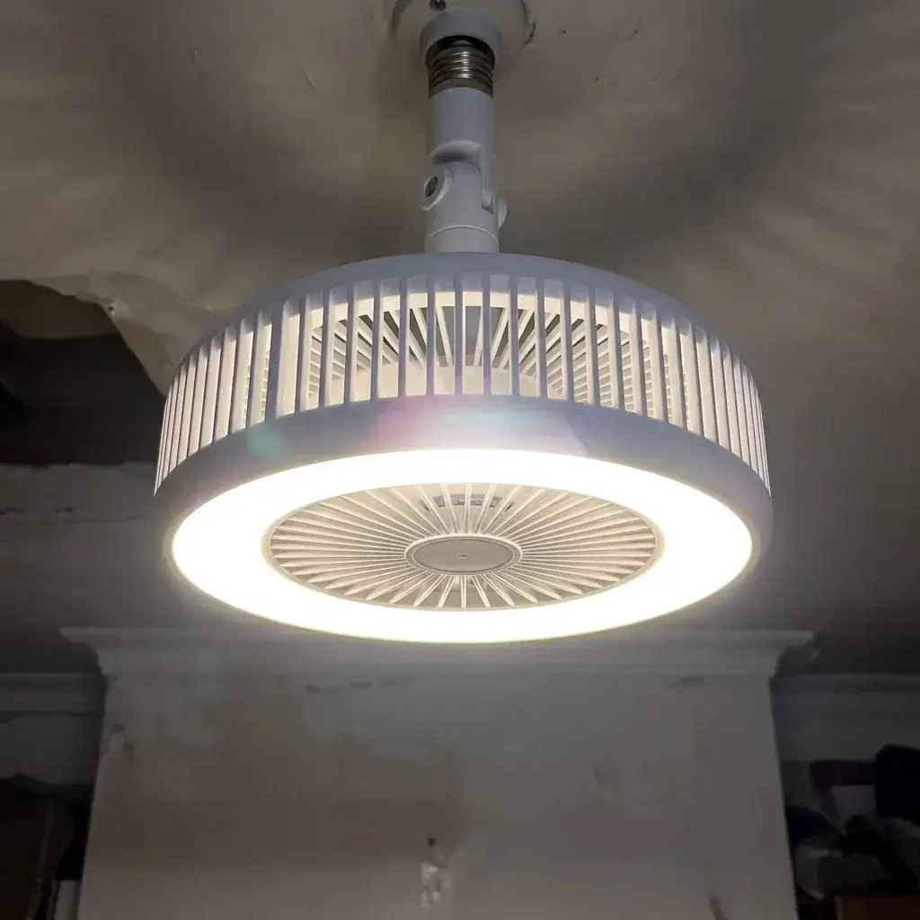 Manos enroscando el ventilador de techo LED en el casquillo de la lámpara